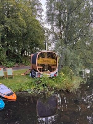Bakifrån med panoramaglas: TimberIN Nordic Square mobilbastu på släp vid en sjö